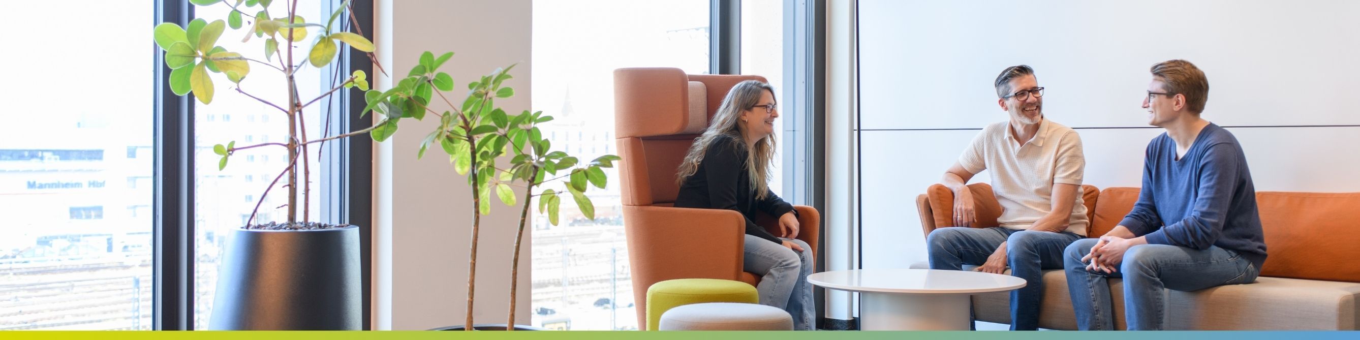 Drei Kolleg:innen im Gespräch, symbolisiert Teamarbeit in einer modernen Büroumgebung
