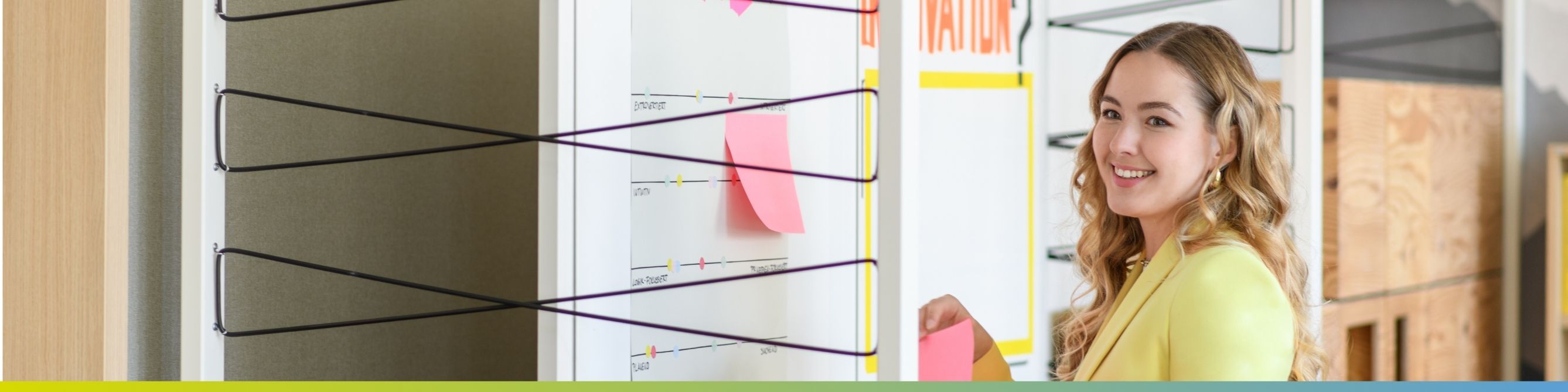 Eine Kollegin steht vor einer Pinnwand, symbolisiert Vergangenheit und Innovation in der Zukunft