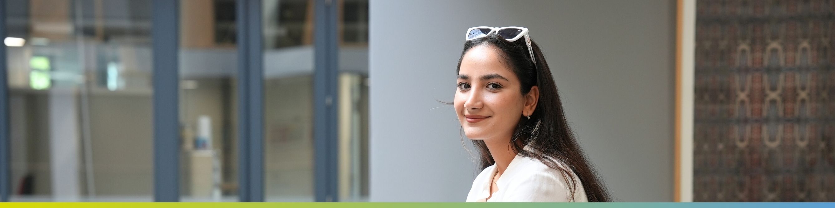 Ein duale Studentin des Fachs Wirtschaftsinformatik lächelt in die Kamera im Büro in Wiesbaden